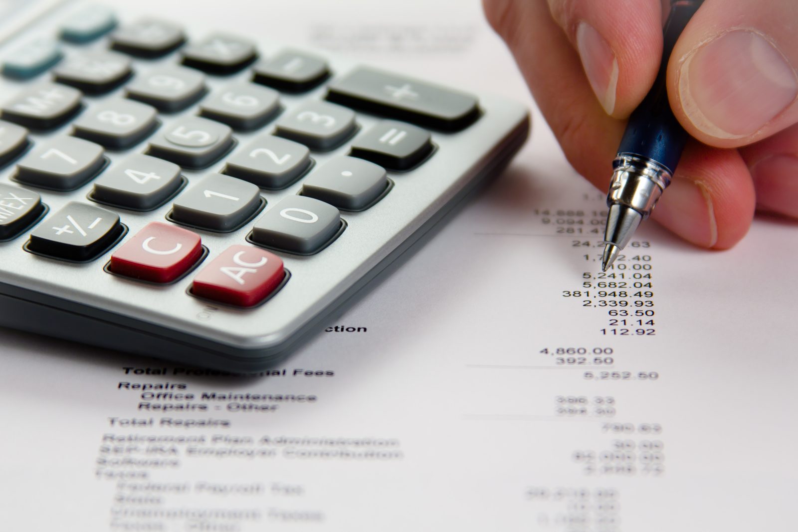 Closeup of a hand using a calculator alongside a pen and financial statement, representing free insurance planning calculators