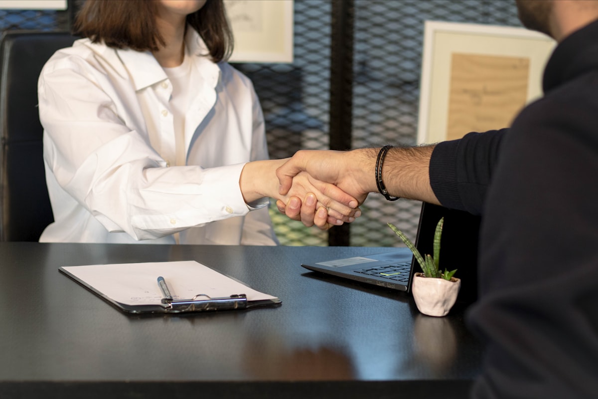 Insurance agent shaking hands with a client across a desk while reviewing health coverage paperwork
